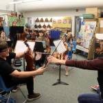 Zack Clark, right, of the visiting Simply Three string trio borrows a violin from Arlo Carlton, 12, to demonstrate a technique during a workshop Friday evening at Sitʼ Eeti Shaanáx̱ Glacier Valley Elementary School for a dozen students in grades 6-12 who are alumni of the Juneau Alaska Music Matters (JAMM) program. The students performed a 30-minute concert Saturday night at Juneau-Douglas High School: Yadaa.at Kalé before Simply Three took the stage to perform the finale of the fall Juneau Jazz & Classics festival. (Mark Sabbatini / Juneau Empire)