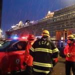 CCFR assistant chief Sam Russell and other officials talk in the rain outside of the Juneau Public Library in downtown. Residents were just starting to arrive at the staging tents around 7 p.m.(Clarise Larson / Juneau Empire)