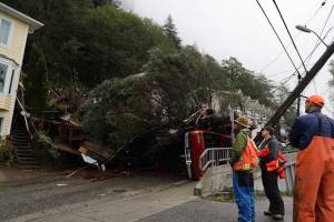 CCFR officials and residents gathered at the section of Gastineau Avenue that sustained damage from the landslide on Monday evening. At the time of 8:30 a.m. on Tuesday officials said they were still trying to assess the damage and no cleanup efforts had started yet. (Clarise Larson / Juneau Empire)