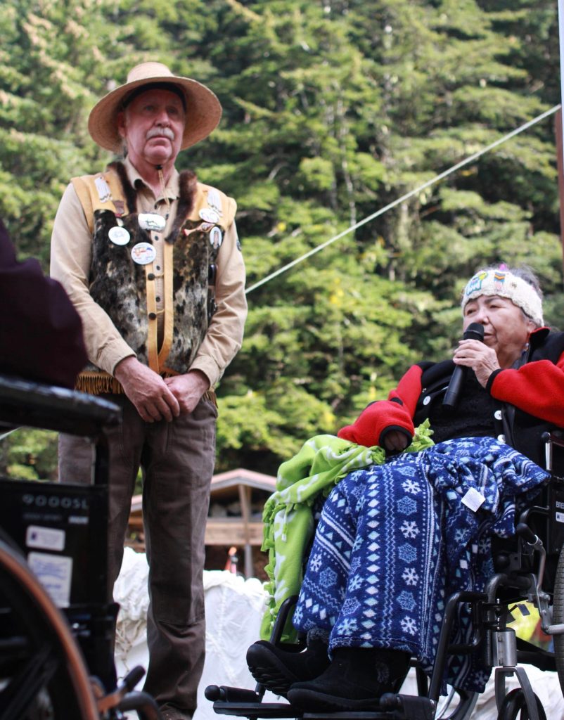 Gordon Greenwald stands near Mary Rudolph during an event commemorating the raising of the XaKooch story pole. During the event, Rudolph, the clan mother for the Chookaneidi, said it was the ancestors dancing through the night in recognition of that event. (Shaelene Grace Moler / For the Capital City Weekly)