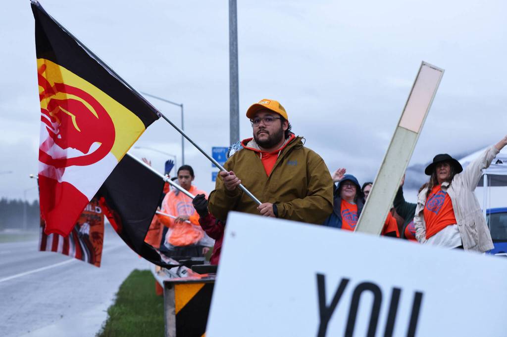 Connor Ulmer holds a flag along Egan Drive for an Orange Shirt Day event. The international day remembers lives lost in the boarding school system and the profound impact systematic forced assimilation has had on Indigenous peoples. (Ben Hohenstatt / Juneau Empire)