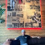 Alaska Native artist Logan Terry poses with his latest art installation currently hanging in the Bearcade above the Crystal Saloon. (Courtesy Photo / David Elrod)