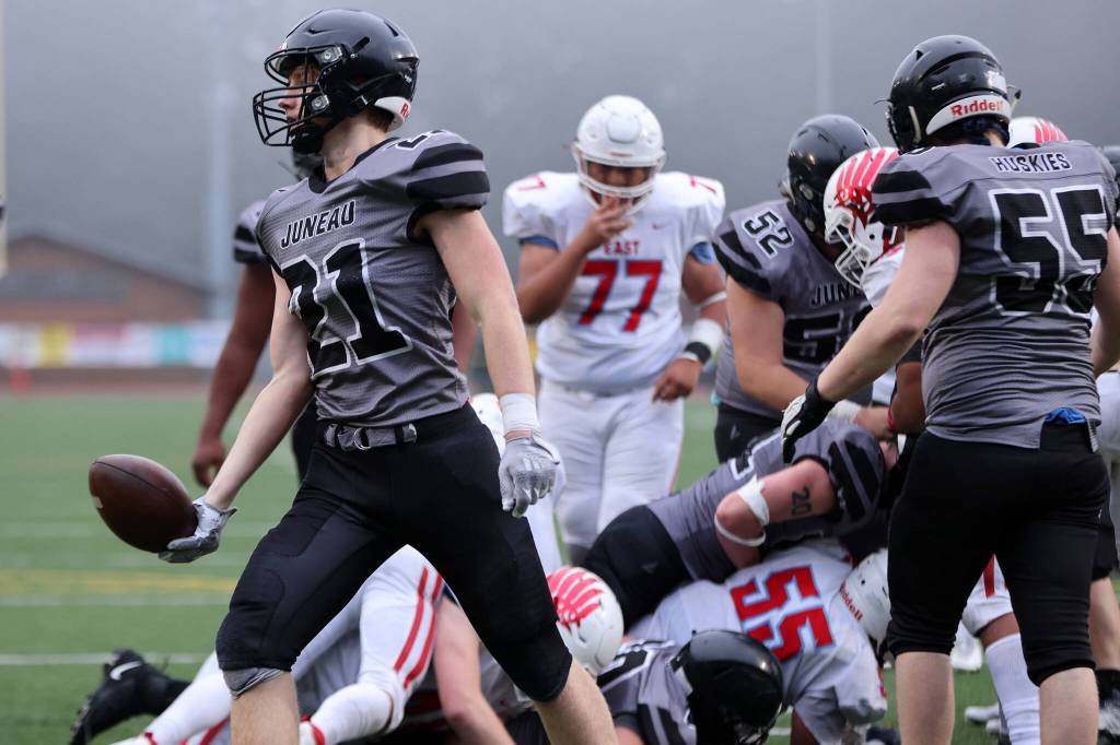 Lucas White (21) tosses the football to the referee after scoring a short rushing touchdown for the Huskies. (Ben Hohenstatt / Juneau Empire)