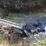 A dump truck lays mangled down an embankment below Glacier Highway near the Auke Bay Ferry Terminal Friday morning after crashing through the guardrail Thursday afternoon. (Clarise Larson / Juneau Empire)
