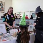 Local artist Kelsey Hoke chats with event goers at her booth featured at the Pumpkin Spice Market on Saturday. Hoke said she has lived in Juneau for the past two years and said she loves the art scene and people here in the capital city and much of her work is based of that. (Clarise Larson / Juneau Empire)