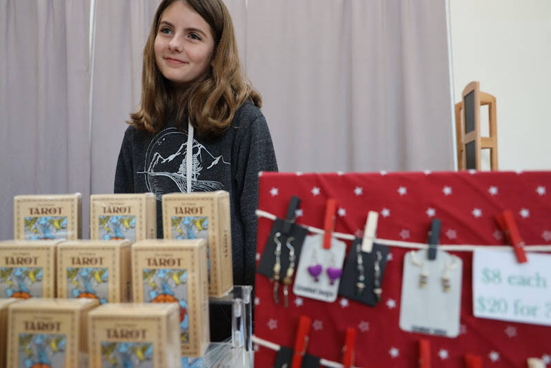 Natalie Mackinnon, a business owner and sixth grade student at Dzantiki Heeni Middle School, stands behind her booth featuring her handmade earrings at the Pumpkin Spice Market on Saturday. At just 11 years old Mackinnon started her own business, Goosebear Designs, last year and said she has been creating sets of earrings with her friends ever since. (Clarise Larson / Juneau Empire)