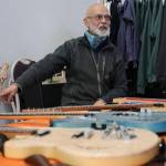 Juneau resident and retired teacher George Gress sits behind a table showing off a array of his many handmade guitars. Gress said after retiring in 2014 after 30 years of teaching, his wife gave him a small woodworking kit to try to introduce a small hobby for him, but it instead led him to create what is now his custom guitar business with products that have been sold worldwide. (Clarise Larson / Juneau Empire)