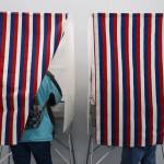 Two residents stand in voter booths Monday morning which marked the start for early and absentee in-person voting across the state for the Nov. 8 general election. (Clarise Larson / Juneau Empire)
