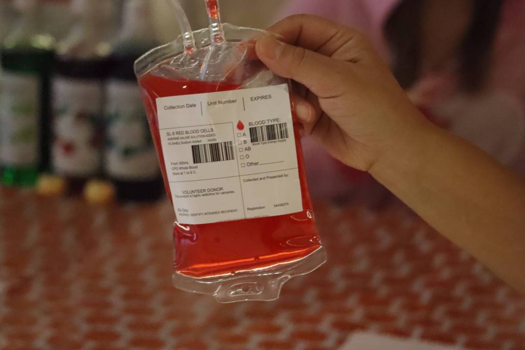 Cheer coach Carlene Nore shows off some of the refreshments served at the JDHS Spirit of Fall Carnival with fruit punch served inside blood bags. (Jonson Kuhn / Juneau Empire)