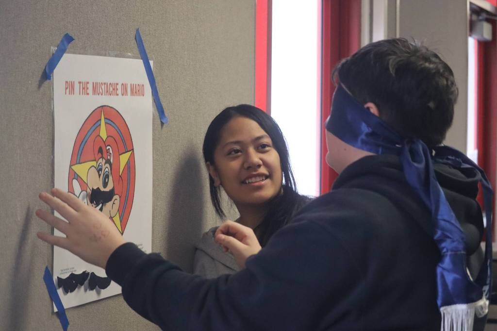 Floyd Dryden Middle School seventh grade students Ginayah Naur and Matthew Haven-Mar participate in one of the games set up to help raise awareness of Movember, a movement that focuses on mens health issues. Students had to try pinning a mustache to familiar cartoon characters while being blindfolded, the mustache is used as a symbol for the movement. (Jonson Kuhn / Juneau Empire)