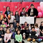Maxine Petersen stands with her parents and third grade class after being surprised with the Alaska 529 $25,000 scholarship award at Kax̱dig̱oowu Héen Elementary on Thursday, Nov. 10. (Jonson Kuhn / Juneau Empire)