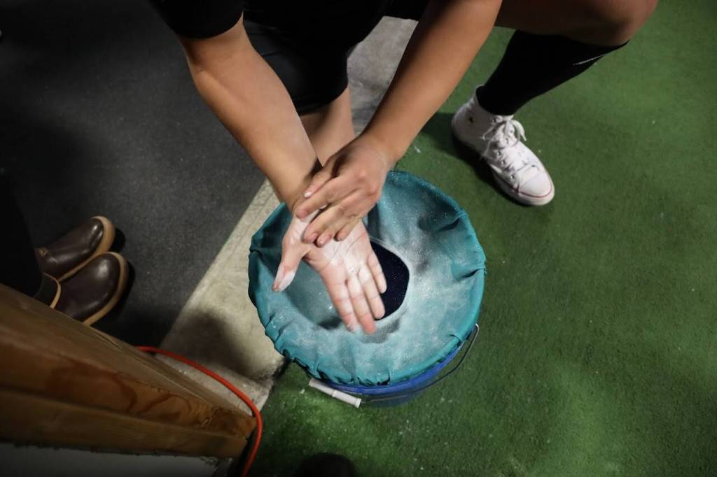A competitor at the USA Powerlifting Coastal Clash competition adds chalk to his hand before heading to the bar to deadlift Monday. (Clarise Larson / Juneau Empire)