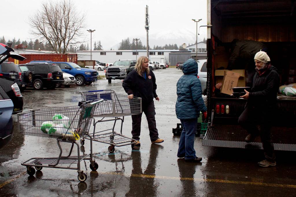 Volunteers load food for Thanksgiving food baskets into vehicles for delivery Saturday morning in the St. Vincent de Paul parking lot. (Mark Sabbatini / Juneau Empire)