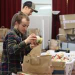 Stig Cunningham, 17, a Raven Correspondence School Honors Program student, loads a bag with Thanksgiving dinner fixings in a community room at St. Vincent de Paul on Thursday. About a dozen students from the homeschool program helped prepare the hundreds of holiday food packages distributed free to people in need. (Mark Sabbatini / Juneau Empire)