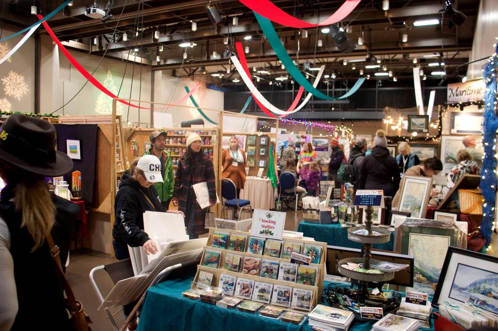 Some of the thousands of people visiting the Juneau Public Market peruse vendors tables in the main room at Centennial Hall on Saturday. About 160 vendors are exhibiting their wares during the three-day event. (Mark Sabbatini / Juneau Empire)