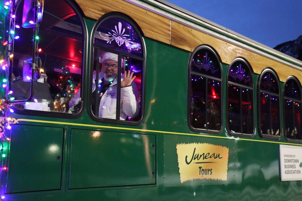 Brett Hutchinson, the driver of the Holiday Trolley, smiles and waves to residents while parked at the Alaska State Library, Archives and Museum Friday evening for the Downtown Business Associations Gallery Walk. (Clarise Larson / Juneau Empire)