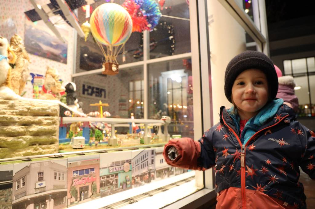Jules Wylie-Ross smiles in front of a window display on the corner of Third and Seward streets during the downtown Business Associations Gallery Walk Friday evening. (Clarise Larson / Juneau Empire)