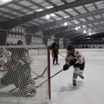 Senior assistant captain Anna Dale attempts to stuff the net during a home game between Juneau-Douglas High School: Yadaa.at Kalé Crimson Bears Varsity hockey team and the Kenai Central Kardinals at the Treadwell Arena Saturday afternoon. (Clarise Larson / Juneau Empire)