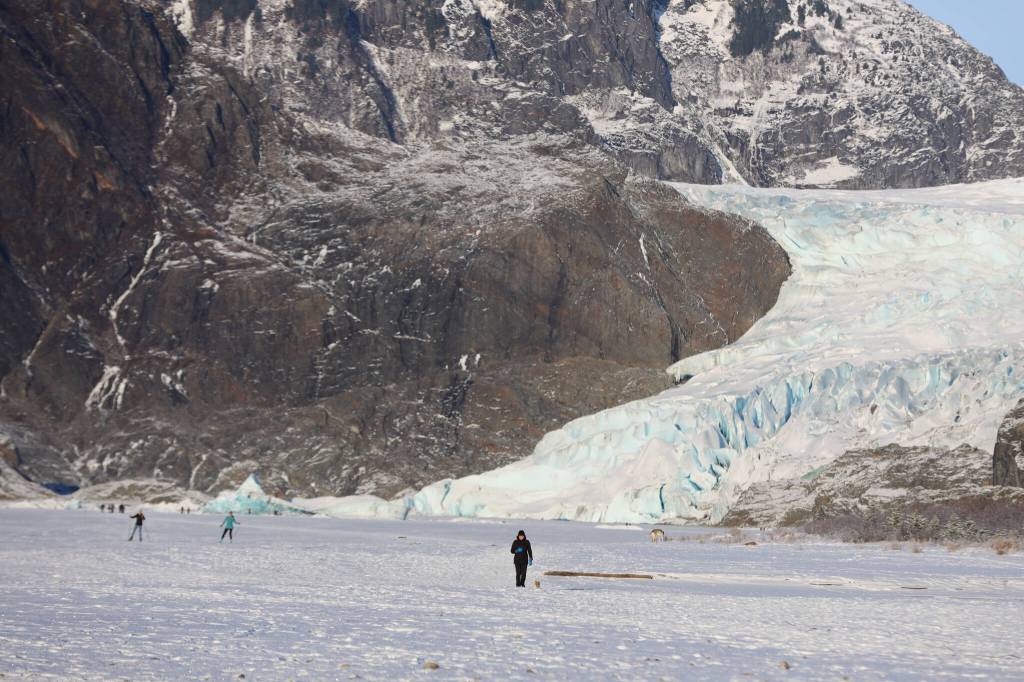 People and dogs traverse the frozen surface Mendenhall Lake on Monday afternoon. Officials said going on to any part of Mendenhall Lake can open up serious risks for falling into the freezing waters. (Clarise Larson / Juneau Empire)