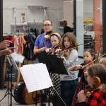 Instructor James Cheng with Juneau Alaska Music Matters conducts students from the intermediate program on Saturday during the annual Holiday Village event at the Mendenhall Mall. (Jonson Kuhn / Juneau Empire)