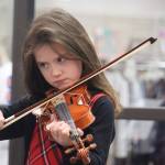 B. Thomas of the beginner level violins with Juneau Alaska Music Matters plays for a full crowd at the Mendenhall Mall during the annual Juneau Holiday Village on Saturday. (Jonson Kuhn / Juneau Empire)