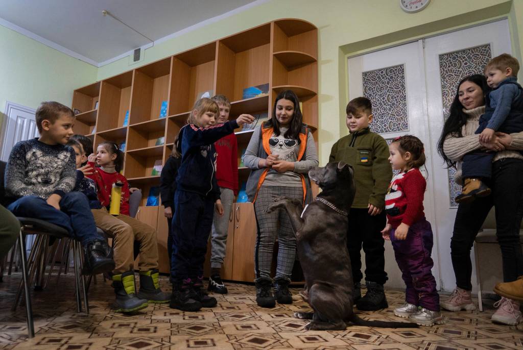 Children traumatized by the war play with an American Pit Bull Terrier Bice in the Center for Social and Psychological Rehabilitation in Boyarka close Kyiv, Ukraine, Wednesday, Dec. 7, 2022. Bice is an American pit bull terrier with an important and sensitive job in Ukraine  comforting children traumatized by the war. The Center for Social and Psychological Rehabilitation is a state-operated community center where a group of people are trying to help those who have experienced a trauma after the Feb. 24 Russian invasion, and now they are using dogs like Bice to give comfort. (AP Photo / Vasilisa Stepanenko)