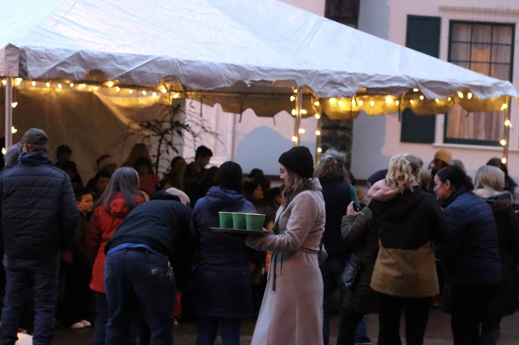 A helper offers hot cider to people waiting outside to get into the governors annual holiday open house Tuesday. (Mark Sabbatini / Juneau Empire)