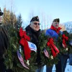 From left to right, Duff Mitchell, Army National Guard veteran, Bill Clutton, Army veteran, and Tom Dawson, Navy veteran stand in a line holding wreaths during a laying of wreaths ceremony for National Wreaths Across America Day on Saturday afternoon. (Clarise Larson / Juneau Empire)