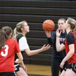 JDHS head coach Tanya Nizich stands between junior Mila Hargrave (black) and senior Ashley Laudert (red), with #13 junior Chloe Casperson nearby on a Wednesday night practice. (Jonson Kuhn / Juneau Empire)
