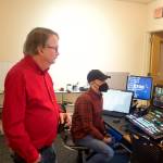 Bill Legere, left, president and general manager of KTOO, and video producer Will Mader watch local politicians and residents in a hallway at the Alaska State Capitol on Thursday as the Juneau delegation of the Alaska State Legislature hosts their annual holiday open house. The studio room is among the numerous additional and higher-technology installations at the stations building during Legeres tenure. (Mark Sabbatini / Juneau Empire)