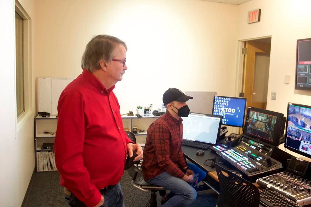 Bill Legere, left, president and general manager of KTOO, and video producer Will Mader watch local politicians and residents in a hallway at the Alaska State Capitol on Thursday as the Juneau delegation of the Alaska State Legislature hosts their annual holiday open house. The studio room is among the numerous additional and higher-technology installations at the stations building during Legeres tenure. (Mark Sabbatini / Juneau Empire)