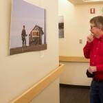Bill Legere, president and general manager of KTOO, examines pictures from around the state by a former photographer in a hallway he selected as favorites to display in a hallway at the station. (Mark Sabbatini / Juneau Empire)