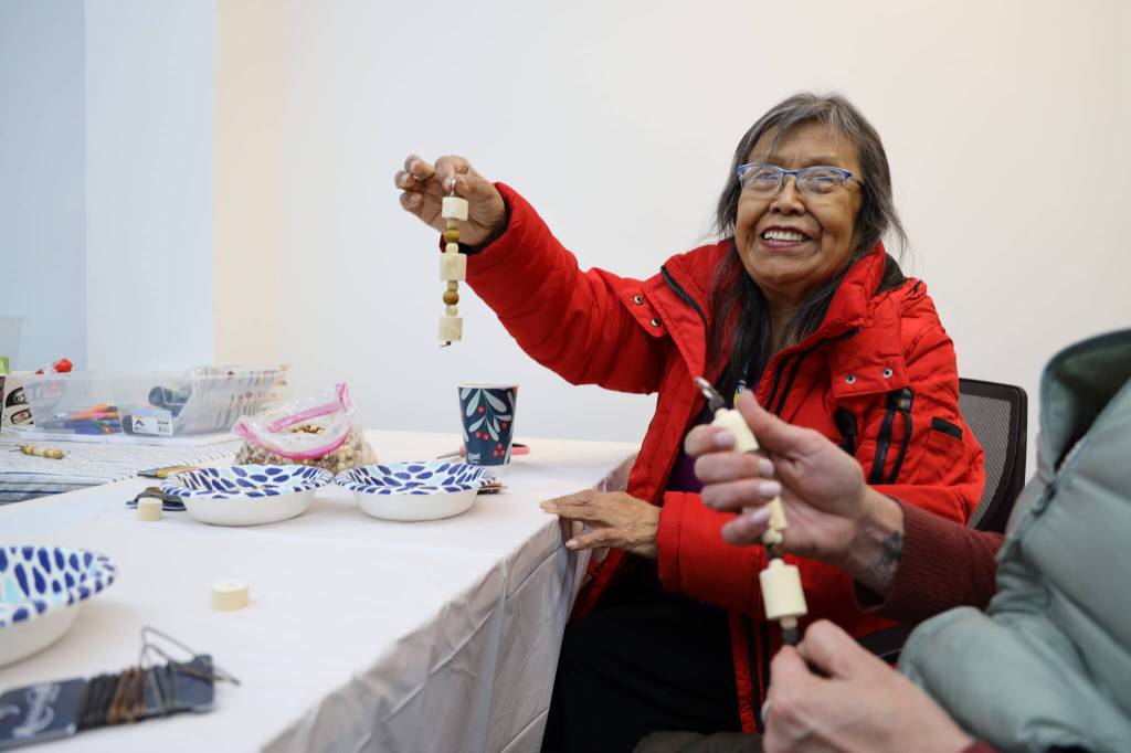 Leona Santiago smiles while holding a beaded key chain made with devils club during a celebration of the winter solstice on Wednesday afternoon at Generations Southeast. According to David Abad, a volunteer at the event who supplied the plant, Devils club often represents protection in Alaska Native cultures. (Clarise Larson / Juneau Empire)