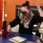 Kendra Hergett wraps a cookbook at Kindred Post located downtown at 145 S. Franklin St. Friday morning as part of their gift wrapping service. Each gift comes complete with two types of wrapping paper, ribbon and a wax seal stamped with the stores logo. Kindred Post will be open from 10 a.m. to 3 p.m. on Christmas Eve. (Jonson Kuhn / Juneau Empire)