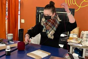 Kendra Hergett wraps a cookbook at Kindred Post located downtown at 145 S. Franklin St. Friday morning as part of their gift wrapping service. Each gift comes complete with two types of wrapping paper, ribbon and a wax seal stamped with the stores logo. Kindred Post will be open from 10 a.m. to 3 p.m. on Christmas Eve. (Jonson Kuhn / Juneau Empire)