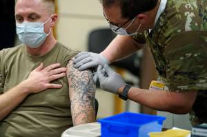 Staff Sgt. Travis Snyder, left, receives the first dose of the Pfizer COVID-19 vaccine given at Madigan Army Medical Center at Joint Base Lewis-McChord in Washington state, Dec. 16, 2020, south of Seattle. U.S. military forces around the world will no longer be required to get the COVID-19 vaccine. The mandate was lifted under an $858 billion defense spending bill passed by Congress and signed into law Friday by President Joe Biden. (AP Photo / Ted S. Warren)