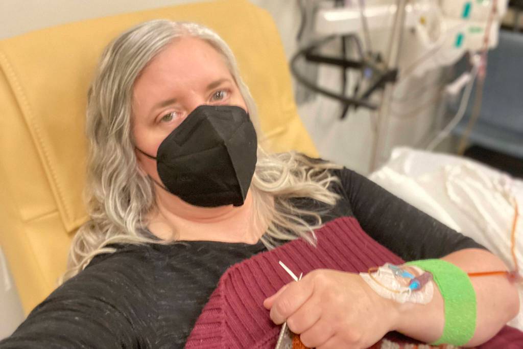 This photo provided by Amy Watson of Portland, Ore., shows her during an iron infusion in December 2022. Watson, approaching 50, says she has never had any kind of recovery from COVID-19. She has had severe migraines, plus digestive, nerve and foot problems. Recently she developed severe anemia. (Amy Watson)