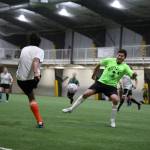 Rachelle Garrett kicks the ball over the leg of opposing player, Ariel Barrios, during a soccer match Monday evening at the Diamond Park Field House a part of the Holiday Cup soccer tournament. (Clarise Larson / Juneau Empire)
