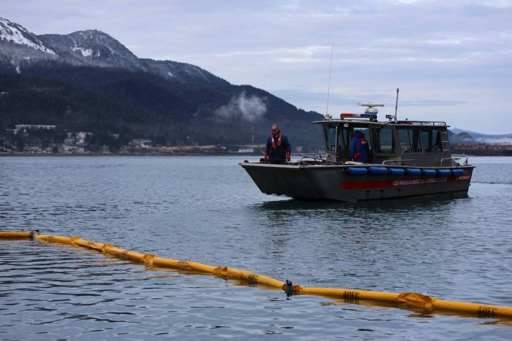 Clarise Larson / Juneau Empire 
On Thursday morning CBJ Docks and Harbors staff place booms in the water surrounding a 107-foot tugboat that sank during the night.