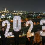 People pose for pictures with a 2023 installation as they celebrate the New Years eve at Mount of Olives overlooking Jerusalems Old City, Saturday, Dec. 31, 2022. (AP Photo/Mahmoud Illean)