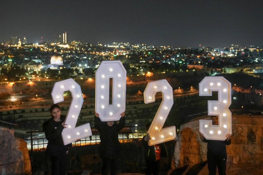 People pose for pictures with a 2023 installation as they celebrate the New Years eve at Mount of Olives overlooking Jerusalems Old City, Saturday, Dec. 31, 2022. (AP Photo/Mahmoud Illean)