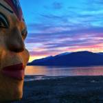 Raven Woman mask by Kristina Cranston is seen in front of a vibrant Wrangell sunset. (Vivian Faith Prescott / For the Capital City Weekly)