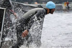An athlete splashes their way into Auke Lake to start the swim leg of the Ironman Alaska. (Ben Hohenstatt / Juneau Empire)