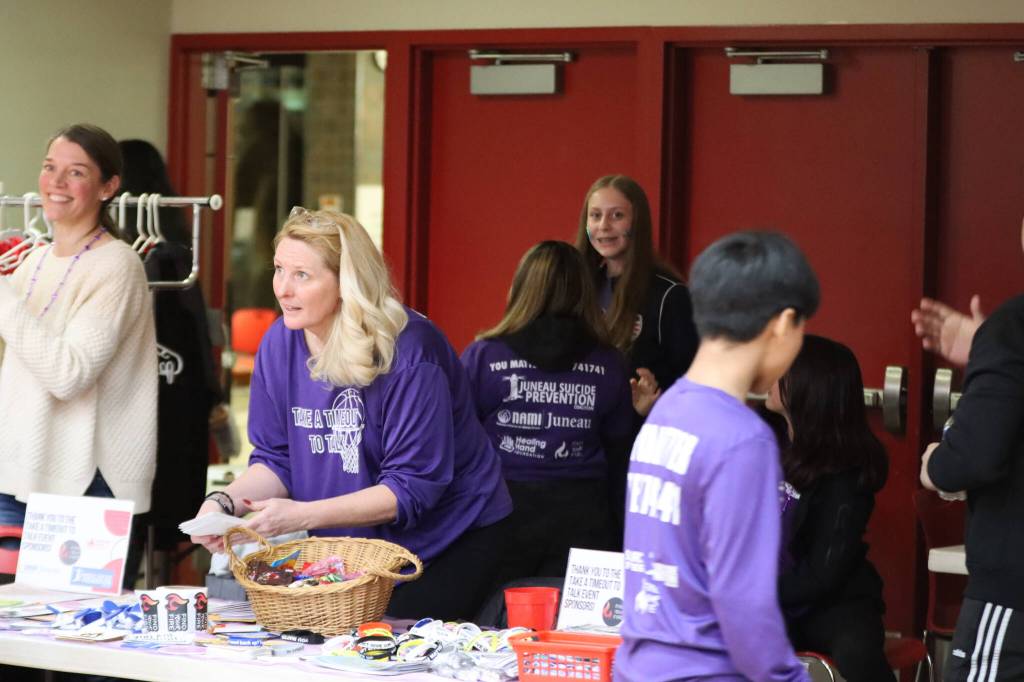 Melissa McCormick and volunteers with nonprofit Find Your Fire hands out T-shirts and swag for the JDHS annual Suicide Prevention Awareness game Wednesday night. McCormick also gave a speech at halftime about the importance of mental health and tossed shirts into the crowd. (Jonson Kuhn / Juneau Empire)