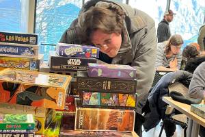 David Holmes digs through a pile of boardgames during Platypus Gamings two-day mini-con over the weekend at Douglas Public Library and Sunday at Mendenhall Public Library. (Jonson Kuhn / Juneau Empire)