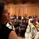Lily Wooshkindein Da.áat Hope, a multiple-medium Juneau-based artist who taught the craft of Chilkat weaving to dozens of student weavers over the past two years, smiles while watching students from the Tlingit Culture Language and Literacy program at Harborview Elementary School perform a dancing-of-the-robes ceremony Wednesday afternoon. (Clarise Larson / Juneau Empire)