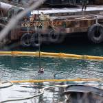 Divers manuever in the water to prepare slings to be placed surrounding a a privately owned 107-foot tugboat that is being recovered by the Coast Guard after it sunk in late December. (Clarise Larson / Juneau Empire)