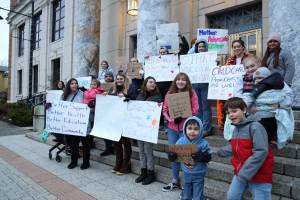 Supporters of a bill that would allow child care providers to participate in collective bargaining with the states Department of Health and establish a state fund to provide grants to childcare providers stand outside the Alaska State Capitol early Friday evening. (Clarise Larson / Juneau Empire)