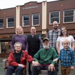 Four generations of the Wiley family pose before the Front Street business the family has owned for fifty years in the historic Blomgren Building. Sally and Fred Wiley, seated, took over the Ben Franklin Store in 1972. Shannon and Mike Wiley stand with Stephen Bishop and Meagan Wiley Bishop and young Nolan Bishop. Today Mike and his daughter Meagan operate the store together. (Michael Penn / For Downtown Business Association)