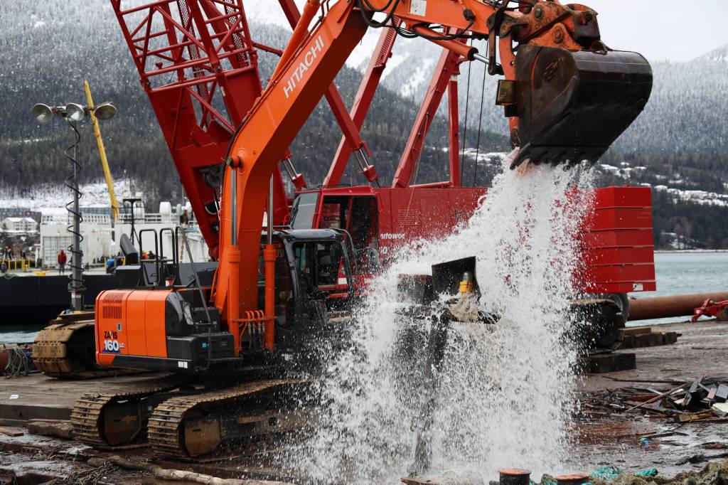 An excavator on a barge dumps floating debris near the shore of Gastineau Channel on Monday morning. The effort was a part of the recovery process of a 107-foot tugboat that sank at a dock south of the cruise ship docks in late December. (Clarise Larson / Juneau Empire)
